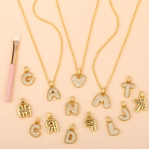 Close-up of 18K gold plated letter pendants with cubic zirconia inlay and hollow back pattern