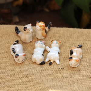 Close-up of 6-piece ceramic cat chopstick rests in various poses on burlap fabric
