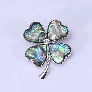 Detailed close-up of a silver four-leaf clover brooch featuring iridescent abalone shell