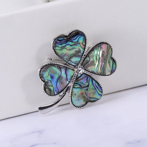 Macro shot of silver clover brooch with iridescent abalone shell and crystal center