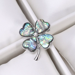 Detailed view of four-leaf clover brooch with natural abalone shell and central crystal