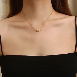 Close-up of a gold-plated evil eye pendant necklace worn by a female model