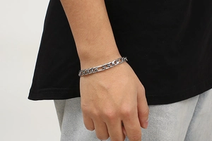 Close-up of polished stainless steel Figaro chain bracelet worn on a person's wrist