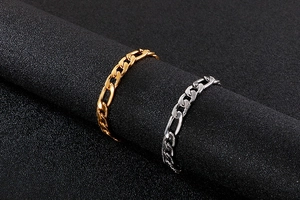 Detailed view of gold and silver curb chain bracelets on a professional display stand