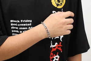 Close-up of a silver stainless steel flat curb link chain bracelet on a male wrist