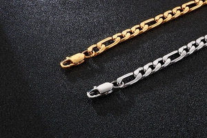 Detailed view of silver and gold Figaro chains with lobster clasps on black texture