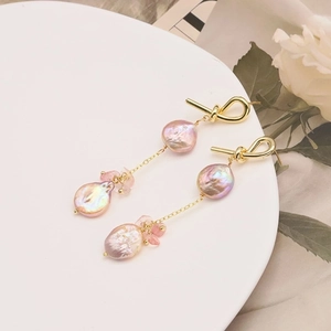 Close-up of pink baroque pearl drop earrings with 18k gold plating on white decor