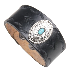 Detail of black embossed leather bracelet with silver skull motif and blue turquoise stone