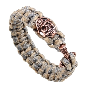 Close-up of paracord survival bracelet with gray and beige weave and bronze skull clasp