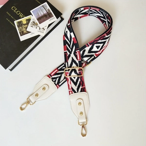 Detail of wide woven strap with geometric pattern and gold-tone metal buckles