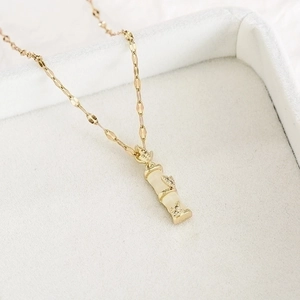 Close-up of golden bamboo pendant with jade-like stone and sparkling crystal details