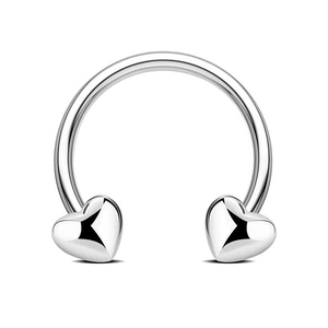Macro detail of silver horseshoe piercing with heart-shaped ends and polished finish