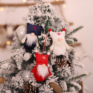 Three Christmas gnome hanging ornaments with snowflake hats on a snowy tree