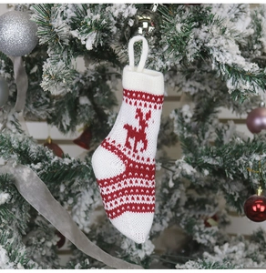 Détail d'une chaussette de Noël en tricot rouge et blanche avec motifs de renne sur sapin