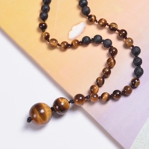 Macro detail of natural tiger eye and lava stone beads on a vintage woven necklace