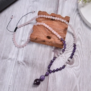 Macro detail of natural rose quartz and amethyst beads with adjustable black cord necklace
