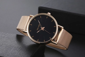 Close-up of rose gold Milanese mesh strap and black dial of a minimalist quartz watch