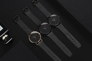 Detailed close-up of three men's quartz watches with Milanese mesh straps on black texture
