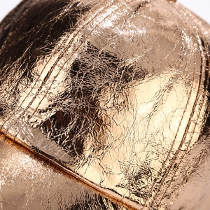 Detail of metallic gold baseball cap featuring pleated texture and mirror finish texture