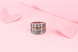 Macro shot of two-tone 304 stainless steel wide ring with inset crystals on pink background