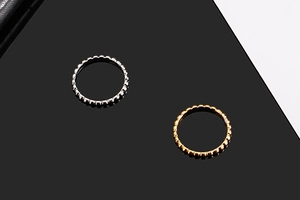 Macro shot of gold and silver beaded rings on a reflective black background