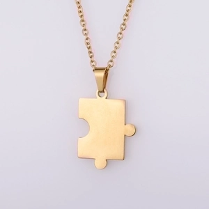Macro detail of golden puzzle piece pendant necklace with a brushed metallic finish