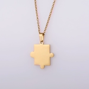 Close-up of golden puzzle piece pendant necklace with delicate polished cable chain