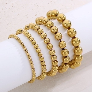 Five-piece set of gold beaded elastic bracelets with polished metallic mirror finish