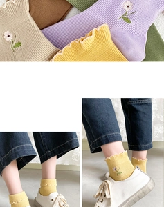 Macro view of floral embroidery and elastic ruffle cuffs on cotton knit ankle socks