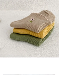 Close-up of floral embroidery and lettuce edge trim on folded cotton knit socks