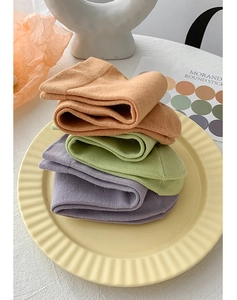 Close-up of Morandi color cotton knitted socks neatly stacked on a decorative plate