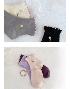 Detailed view of floral embroidery and scalloped edges on soft ribbed cotton socks