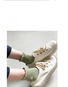 Close-up of light green knit socks with flower embroidery and scalloped edges for women