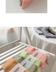 Close-up of multi-colored cotton mid-calf socks with paper packaging on a wooden stool
