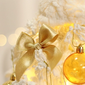 Mini flocked white Christmas tree with gold bows and LED lights for desktop decor