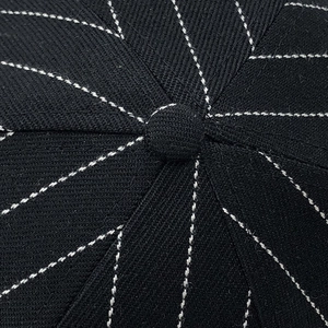 Macro view of the pinstripe cotton fabric and top button detail on a black baseball cap
