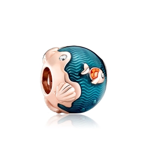 Macro shot of rose gold charm with blue ocean waves, fish and shell details