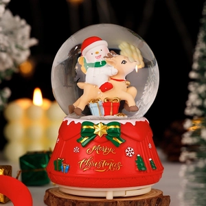 Christmas musical snow globe with snowman riding a reindeer on a red festive base