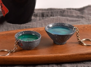 Close-up of creative ceramic-style resin cup keychains in green and blue liquid texture