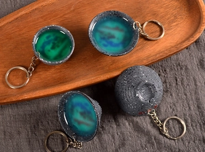 Macro detail of Jianzhan style keychain with glossy turquoise glaze and matte dark finish