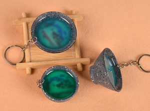 Macro detail of creative tea bowl keychain with green resin liquid and gold speckles