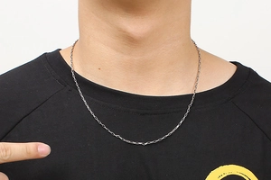 Close-up of minimalist silver rectangular link chain necklace worn by male model