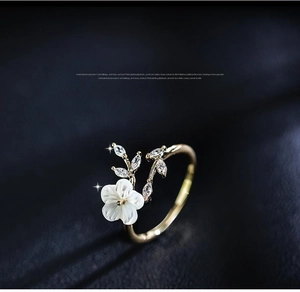 Macro shot of gold adjustable ring featuring white resin rose and cubic zirconia leaves