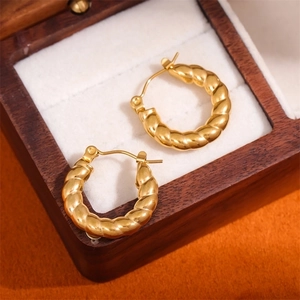 Chic twisted gold hoop earrings in a wooden jewelry box with a macro focus on texture