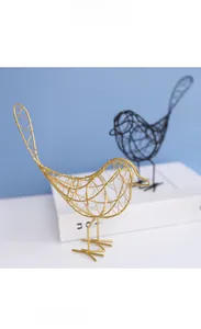 Détail de figurines d'oiseaux en fil métallique doré et noir sur un bureau minimaliste