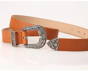 Close-up of brown vintage leather belt with ornate silver-engraved buckle and metal tip