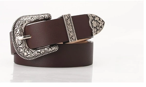 Detail of vintage brown leather belt with ornate silver floral engraved metal buckle