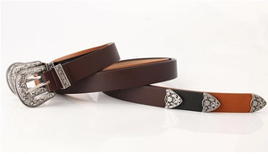 Detail of vintage belt with silver engraved buckle and dual-tone brown black leather strap