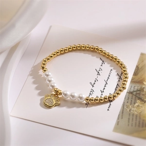 Close-up of gold beads and white pearls bracelet featuring a crystal cat paw pendant
