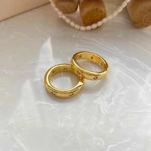 Anillos elegantes de latón bañados en oro con circonitas sobre fondo de mármol